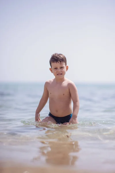 Menino Adorável Que Usa Maiô Preto Está Água Rasa Praia — Fotografia de Stock