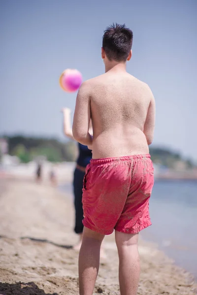 Молодой Парень Красном Купальнике Играет Мячом Пляже Солнце — стоковое фото