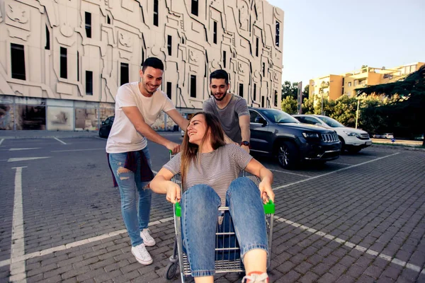 Zwei Freundinnen Fahren Mädchen Mit Einkaufswagen Auf Parkplatz — Stockfoto