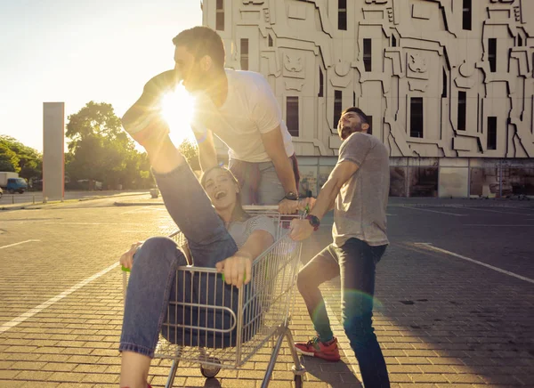 Zwei Lachende Junge Freunde Schieben Ihren Freund Einem Einkaufswagen Über — Stockfoto