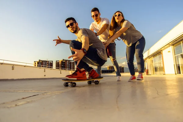 Tři Bezstarostné Přátelé Hrát Longboard Balkóně Budovy Při Západu Slunce — Stock fotografie