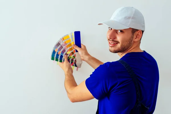 壁のための色を選択する彼の手の中にカラーガイドを持つ若い画家 — ストック写真
