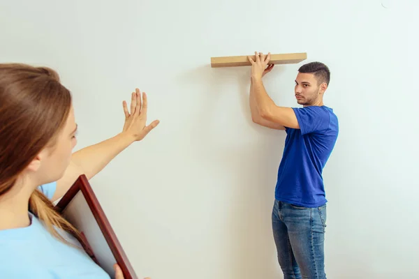 Mujer Joven Mostrando Novio Para Colgar Estante Pared Casa — Foto de Stock