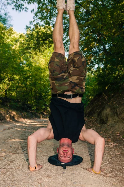 筋肉男の林道で倒立をしながら運動 — ストック写真