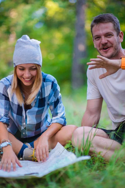 若いカップルが休憩し 森の中の地図をチェックします 夏の山の中のハイキングのコンセプト — ストック写真