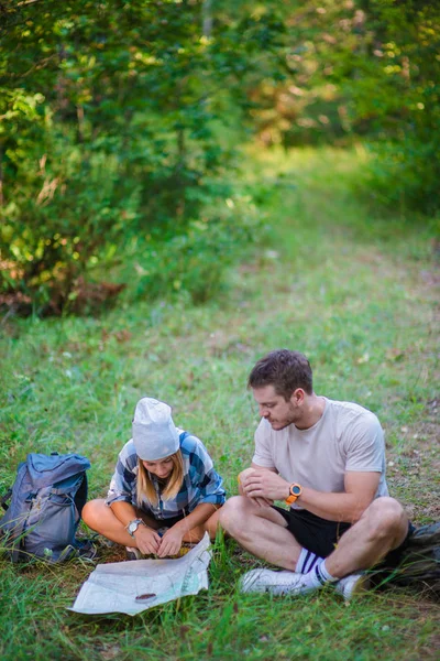 年轻夫妇在森林里休息和查看地图 夏天登山的概念 — 图库照片