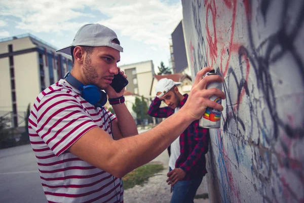 Giovane Uomo Che Parla Sul Suo Smartphone Mentre Disegna Grafitti — Foto Stock