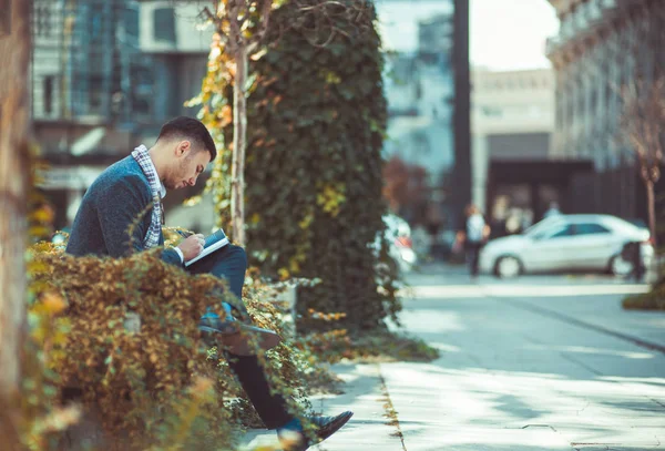 都市の男は屋外で 深刻な非常に彼のノートに書いている間興味を探して — ストック写真