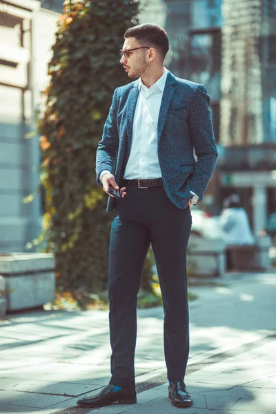 屋外で立って 彼の携帯電話を保持しているスーツを着て自信を持っての実業家 — ストック写真