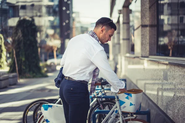 一个城市的公共汽车司机正把手放在自行车的外壳上 站在城市广场上他停放的自行车附近 — 图库照片