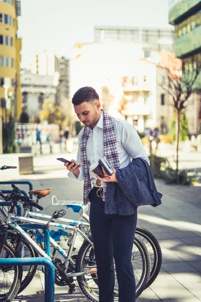 Urban Biznesmen Trzyma Książkę Ręce Patrząc Jego Telefon Stojąc Obok — Zdjęcie stockowe