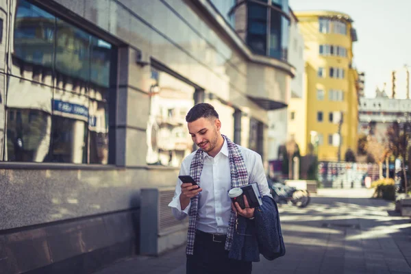 都市のビジネスマンは晴れた日を楽しんで 彼の携帯電話を見ながら通りを歩いて — ストック写真