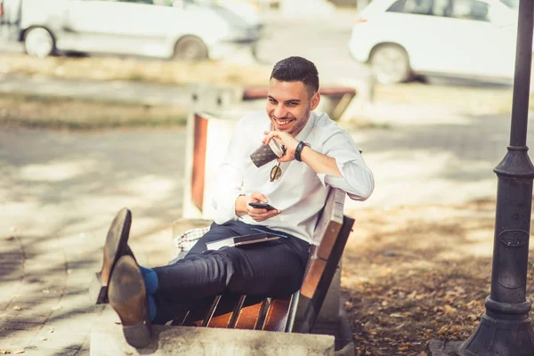 Joven Empresario Feliz Está Tumbado Banco Parque Sonríe Mientras Sostiene —  Fotos de Stock