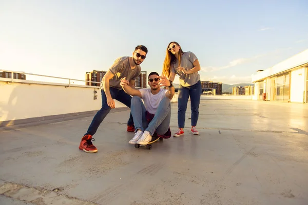 Tres Amigos Divierten Mientras Chico Sienta Monopatín Atardecer — Foto de Stock