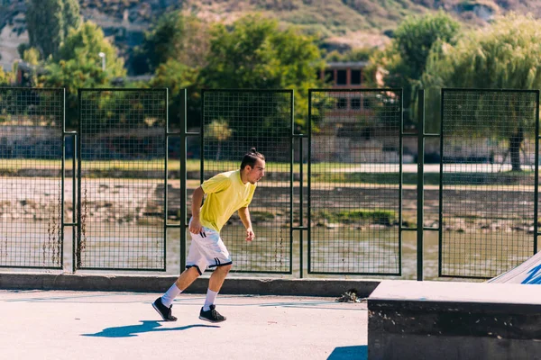 训练日的一个年轻的跑酷男子跳过障碍在 Skatepark — 图库照片