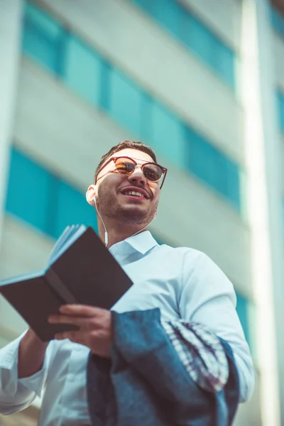 Glücklicher Junger Mann Steht Mit Kopfhörer Und Notizbuch Auf Der — Stockfoto