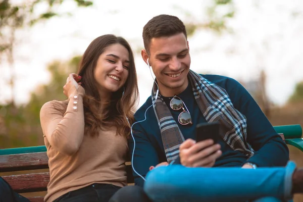 Junges Paar Hört Musik Lächelt Schaut Auf Das Telefon Und — Stockfoto