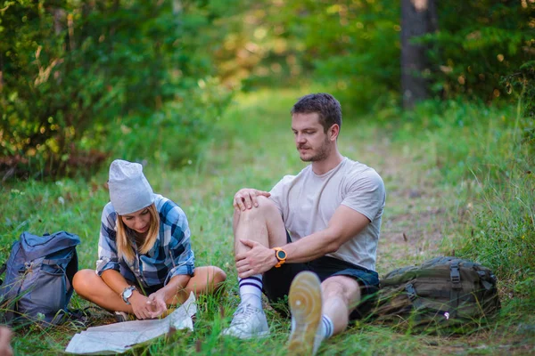 若いカップルが休憩し 森の中の地図をチェックします 夏の山の中のハイキングのコンセプト — ストック写真