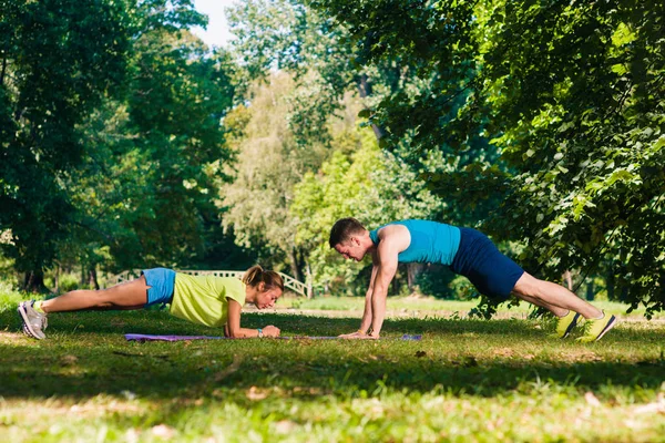 公園の芝生の上のアスレチック カップル トレーニング プッシュ アップ — ストック写真