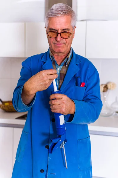 Sênior Faz Tudo Cozinha Enquanto Segurando Calafetagem Arma — Fotografia de Stock