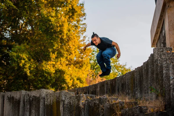 公園内の壁を飛び越えてトレーニング パルクールしながら強い男 — ストック写真