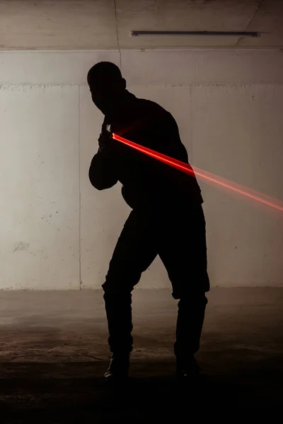 Sylwetka Człowieka Stojący Ciemnym Pokoju Trzymając Pistolet Laserowy — Zdjęcie stockowe