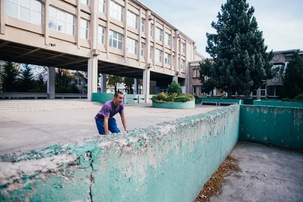 市街地でコンクリート壁を飛び越えるトレーニング パルクールしながらストロングマン — ストック写真