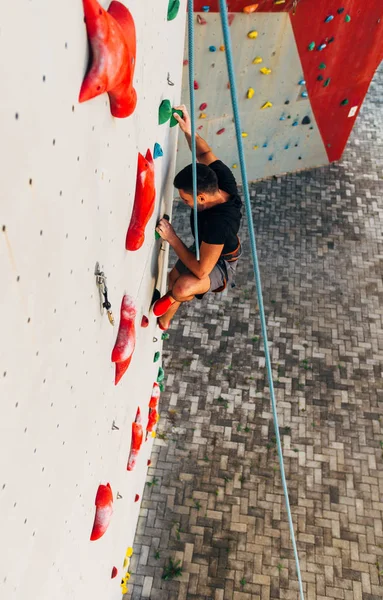 Człowiek Noszący Linę Wspinający Się Bardzo Wysoką Ścianę Wspinaczkową — Zdjęcie stockowe
