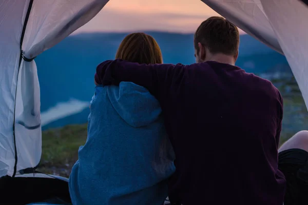 夕日に山の上でたき火をして山の景色を楽しむ若いカップル — ストック写真