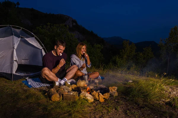 Ungt Par Avkopplande Vid Lägerelden Äta Rosted Marshmallows Och Dricka — Stockfoto