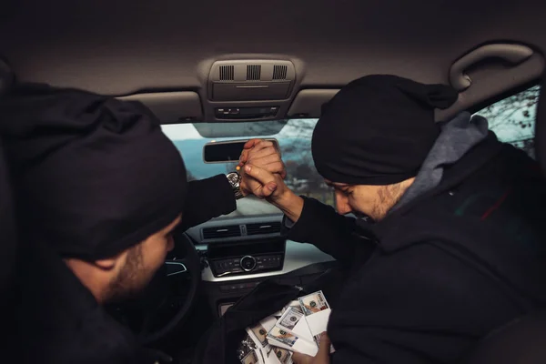 After the successful bank robbery, the thieves are sitting in the car showing off their money and celebrating the win over the law they had.