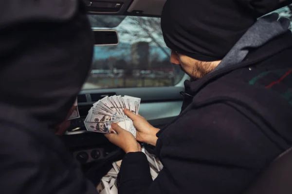 After the successful bank robbery, the thieves are sitting in the car showing off their money and celebrating the win over the law they had.