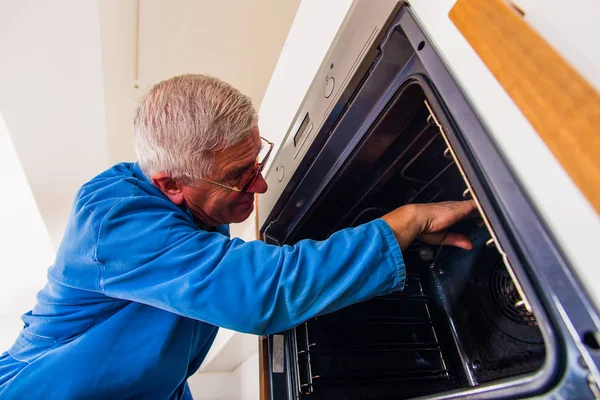Reifer Handwerker Blauen Arbeitsanzug Der Den Ofen Der Küche Repariert — Stockfoto