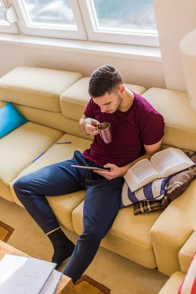 Junger Mann Trinkt Kaffee Und Schaut Auf Sein Tablet — Stockfoto