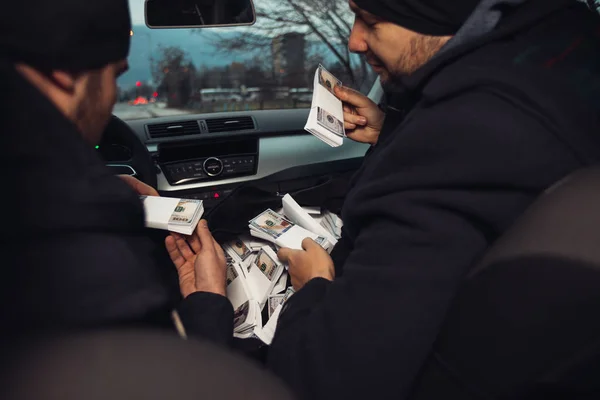 After the successful bank robbery, the thieves are sitting in the car showing off their money and celebrating the win over the law they had.