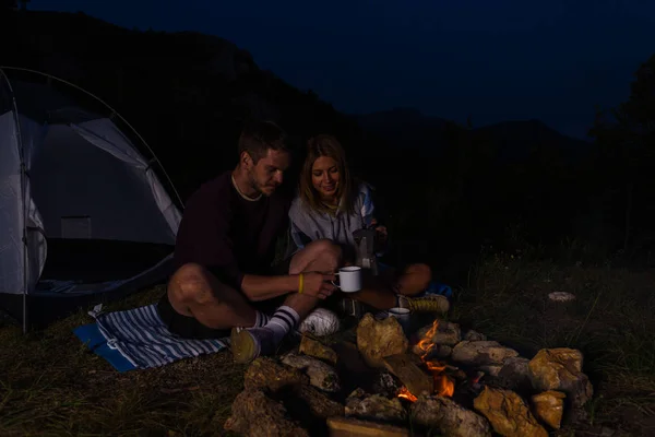 Pareja Joven Relajándose Junto Fogata Tomando Café Colina Del Bosque —  Fotos de Stock