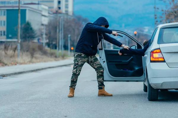 El ladrón de coches está sacando al dueño del coche de su coche y tratando de — Foto de Stock