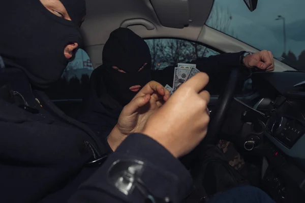 Два грабителя в масках считают деньги, которые они заработали, сидя в — стоковое фото