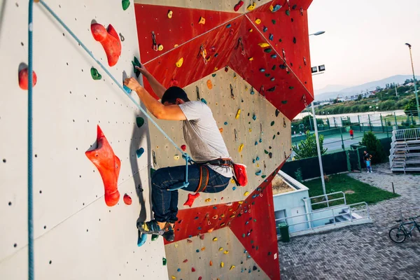 Młody sportowe człowiek wspinaczka na praktyce zamontować ściany zewnątrz — Zdjęcie stockowe