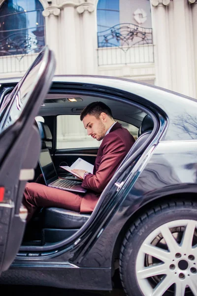 Hombre de traje leyendo su cuaderno en el coche — Foto de Stock