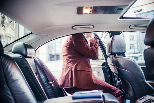 Biznesmen w fioletowym garniturze uzyskanie w samochodzie — Zdjęcie stockowe