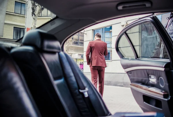 Elegante hombre de negocios hablando por teléfono celular cerca de la limusina — Foto de Stock