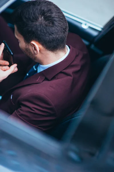 Ung affärsman tittar på hans mobiltelefon medan bekvämt sitta — Stockfoto