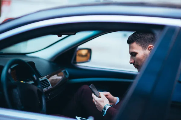 Ung affärsman tittar på hans mobiltelefon medan bekvämt sitta — Stockfoto