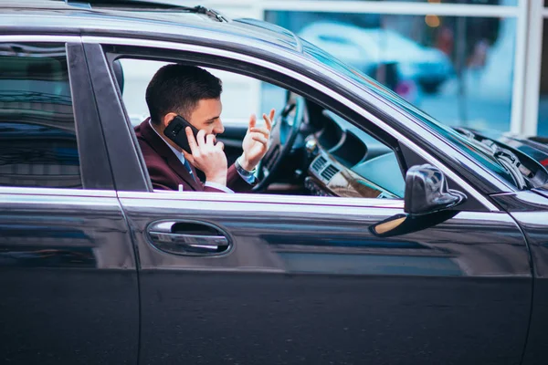 Um homem de negócios sério está tendo uma conversa em seu telefone enquanto — Fotografia de Stock