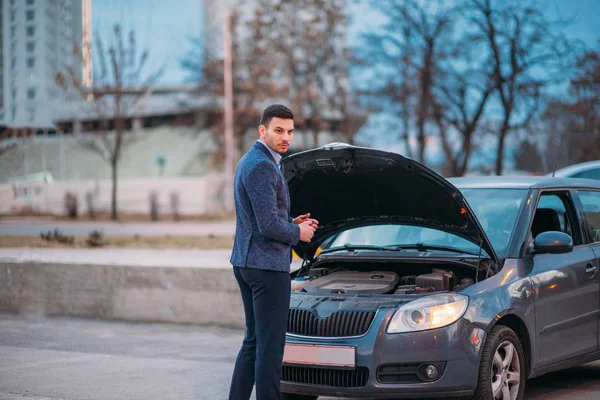 Um trabalhador cansado está de pé ao lado de seu carro formalmente vestido e — Fotografia de Stock