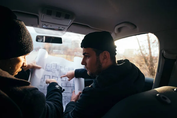 Dva násilné zloději sedí v autě, při pohledu na plán t — Stock fotografie