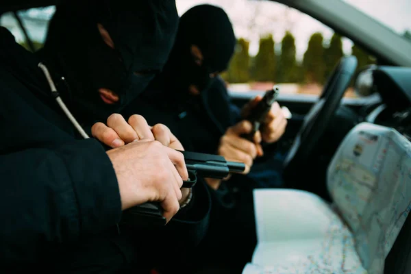Bank robbers with their masks on pointing at the map prepared fo