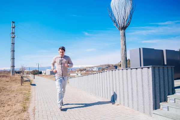 Een hijgend atleet lopen snel op een track tijdens het dragen van headphon — Stockfoto