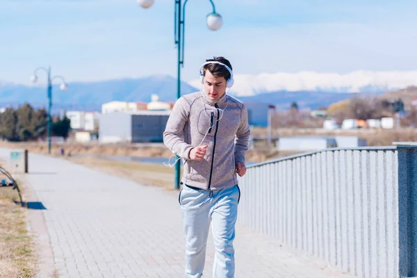 Een hijgend atleet lopen snel op een track tijdens het dragen van headphon — Stockfoto